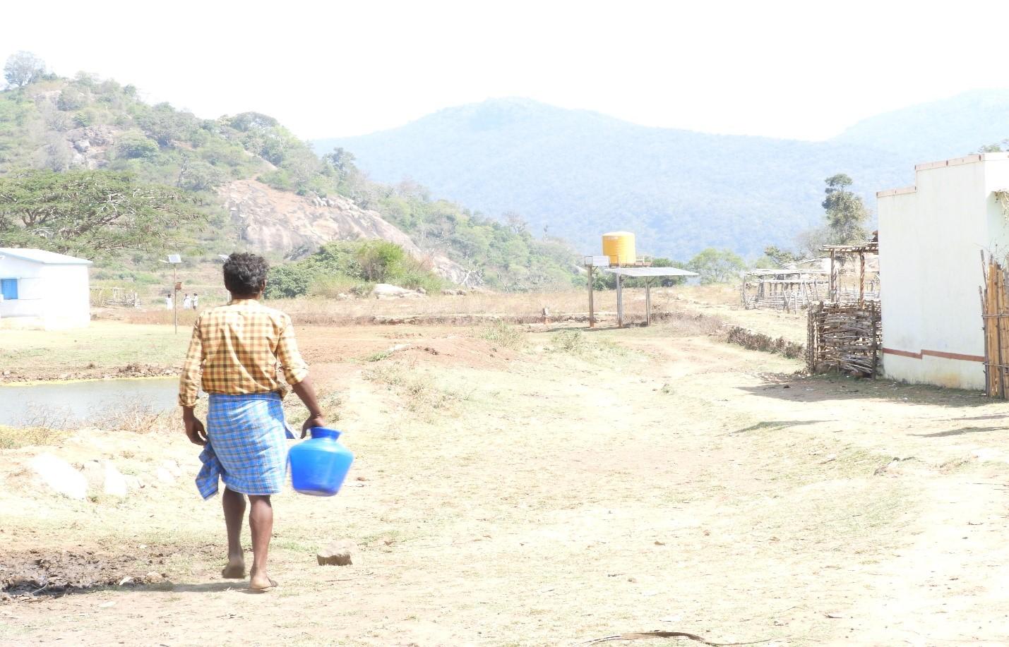 Person walking away holding water carrying pot